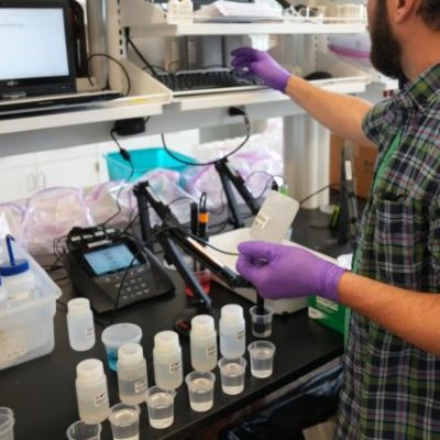 A technician running water samples on bench instruments in a testing laboratory
